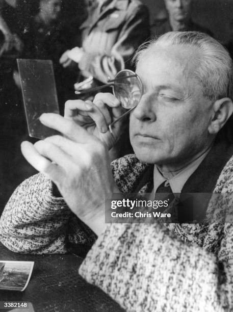 Heinrich Hoffmann Hitler's photographer and confidante of high ranking Nazis, examines a negative through a magnifying glass. Hoffmann is under open...