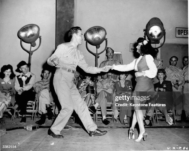 An American serviceman dancing the jitterbug with a young woman.