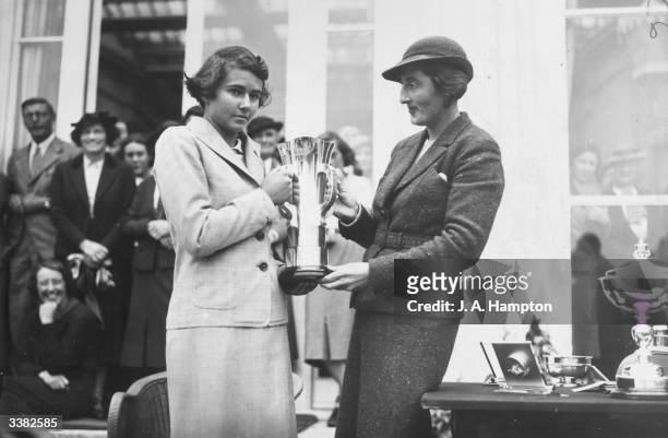 Enid Wilson who won the British Amateur Open presenting the cup to Mlle Vagliano of France winner of the Girl's Open Golf Championships at Stoke...