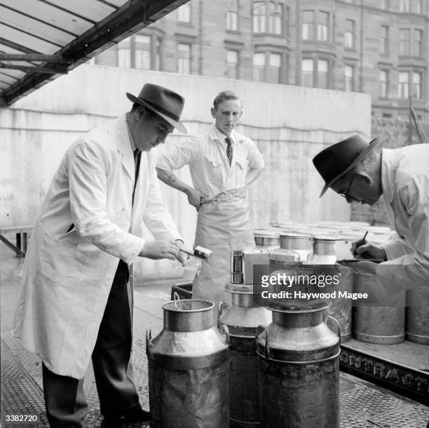 Dairy workers checking milk churns at a depot in Glasgow. Glasgow has many industrial estates which offer ample space for large factories, such as...