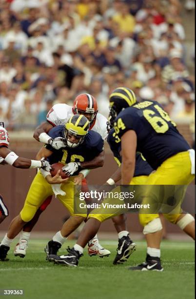 Quarterback Tom Brady of the Michigan Wolverines in action against lineman Vaughn Smith and defensive back Quentin Harris of the Syracuse Orangemen...