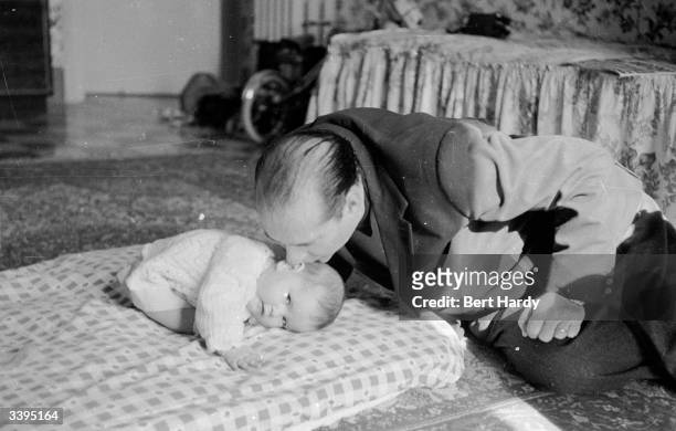 Italian film director Roberto Rossellini and husband of Ingrid Bergman kisses one of his eleven-month-old twin daughters . Original Publication:...