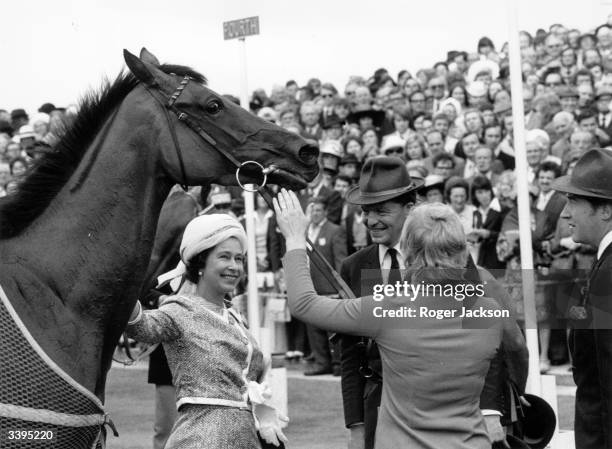 Queen Elizabeth II of Great Britain with her horse 'Highclere' at Epsom racecourse, Surrey.