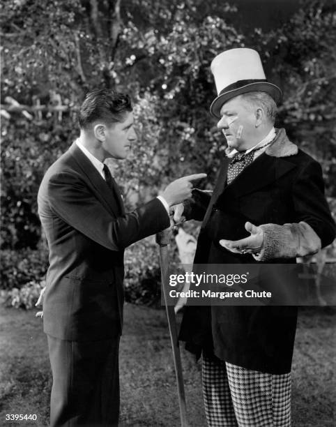 American comedian W C Fields jokes with director A Edward Sutherland during production of the Paramount film 'Poppy'.