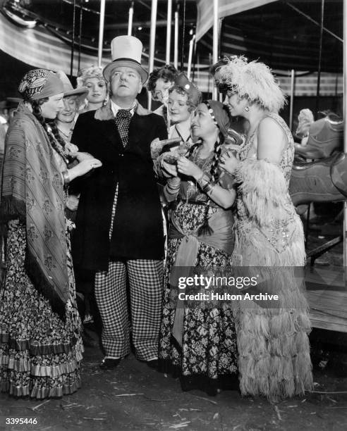 American comedian W C Fields surrounded by society beauties in a scene from the film 'Poppy', directed by A Edward Sutherland for Paramount.