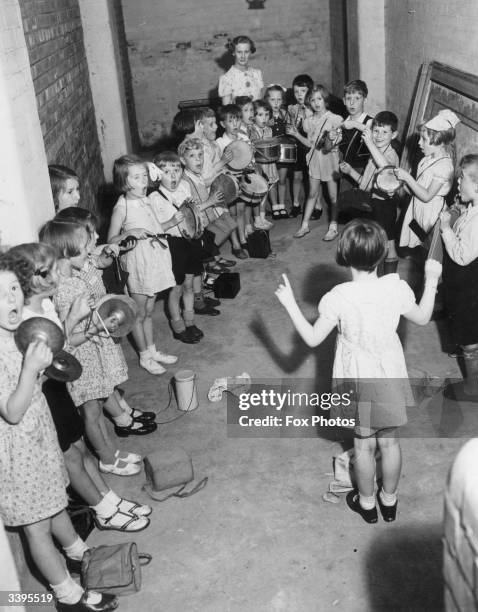 Members of the Wilbraham Infants School percussion band practising in a shelter during an air raid in Manchester. The idea is to entertain the...