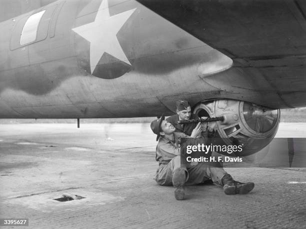 Rudolf Portong of Long Island, USA, shows a Royal Airforce crew worker the mechanism for the ball turret machine gun. American aircrews are...