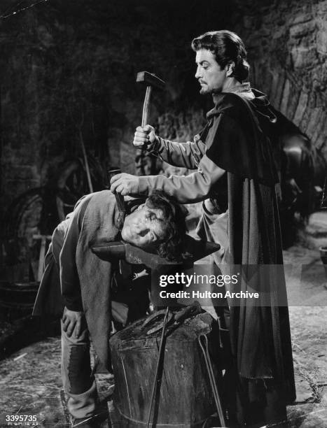 Robert Taylor the stage name of Spangler Arlington Brugh, prepares to remove the shackles from a slave in the film 'Ivanhoe', directed by Richard...