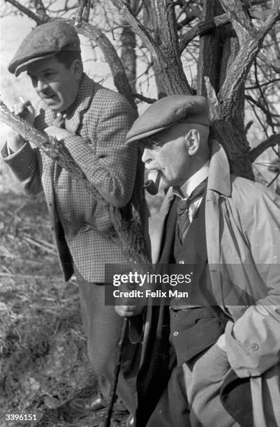 Two men watch a Jack Russell being released into a badger sett while digging for badgers in the Gloucestershire countryside. Original Publication:...