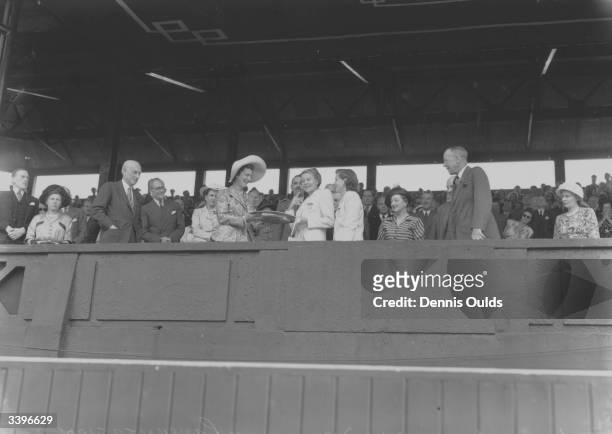 Margaret du Pont of the USA watches as fellow American Louise Brough collects the women's singles trophy from the Duchess of Kent after the final at...
