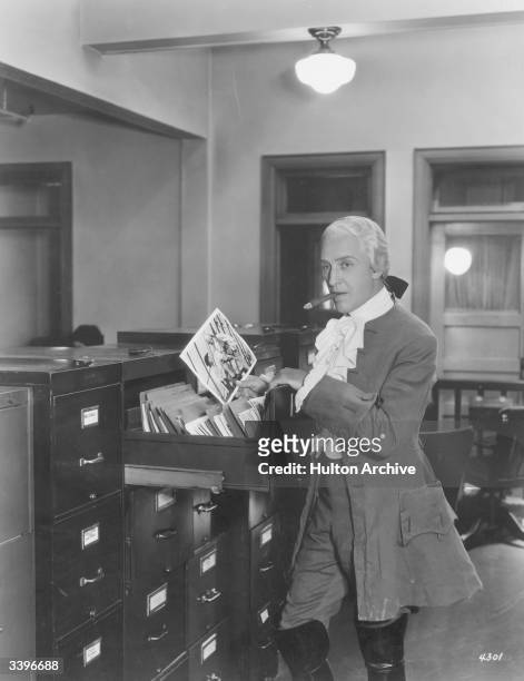 American actor, pianist and composer Otto Kruger looking through pictures of himself in the MGM film of 'Treasure Island' which he is currently...