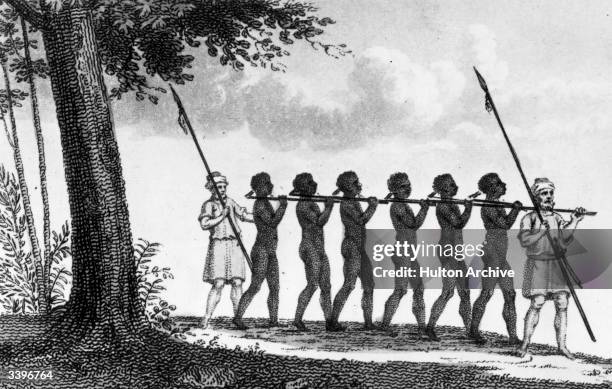 Chain of enslaved people, flanked by men with spears, being taken from the African interior. Original Publication: From 'The World In Miniature'...