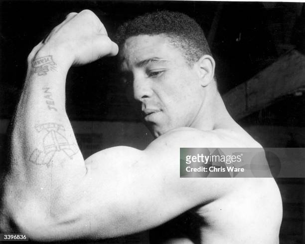British boxer and world middleweight champion Randolph Turpin showing off his tattoos and biceps.