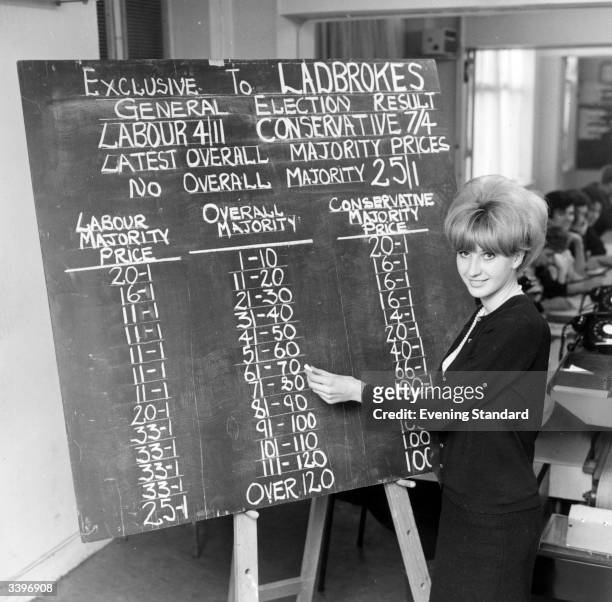 An employee of Ladbroke's writing prices on a blackboard during the General Election.