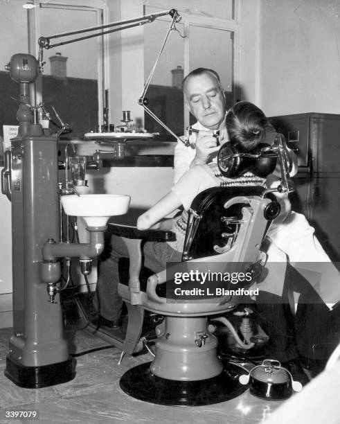 Dentist at work on a young patient in the Woodberry Down Health Centre, Stoke Newington, London, the first comprehensive clinic to be built under the...