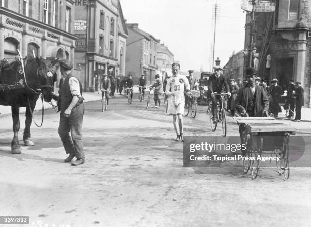 Competitor during a road walking race being followed by spectators on bicycles.