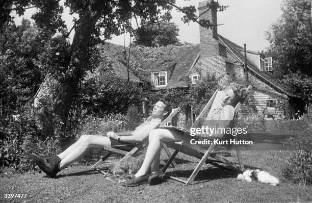 English actor John Mills and his wife playwright Mary Hayley-Bell sunbathing in the garden at their cottage in Denham village, England. Original...