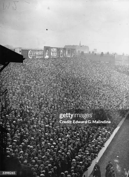 Crowds of hat-wearing football fans at a cup tie match between West Ham United and the Corinthians at Upton Park.