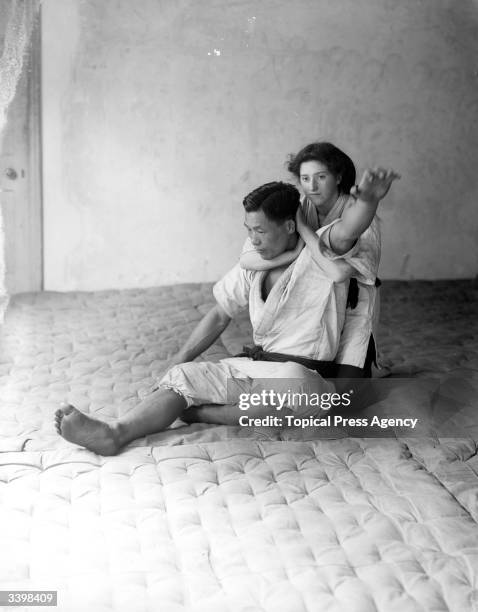 Woman is pictured demonstrating a choke hold on a man in a display of Japanese Jiu-jitsu techniques.