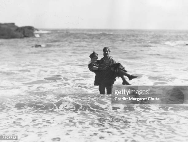Ramon Novarro carries his co-star Marceline Day out of the sea, in a scene from the MGM film 'Road to Romance'.