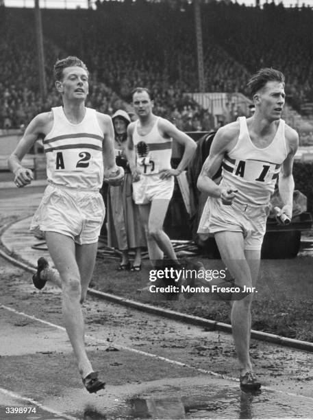 Roger Bannister receiving the baton from B Shewson during the 4 x 1500 metre relay race at the International Athletics meeting between England and...