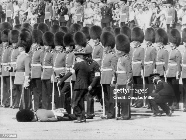 First aid attendants helping a Guardsman, after he fainted due to the heat, during a rehearsal for the Trooping of the Colour in London.