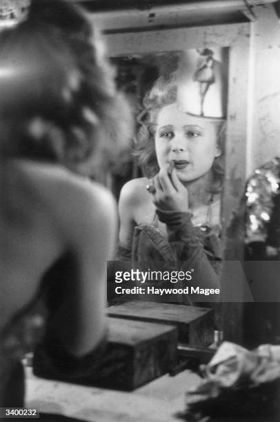 Showgirl puts on her lipstick backstage at the Casino de Paris, a French music-hall which survived through the German invasion. Original Publication:...