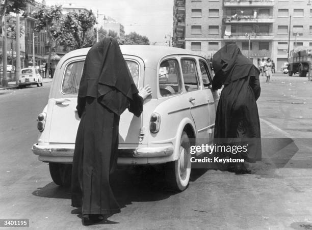 Nuns pushing their broken-down car in a street in Rome.