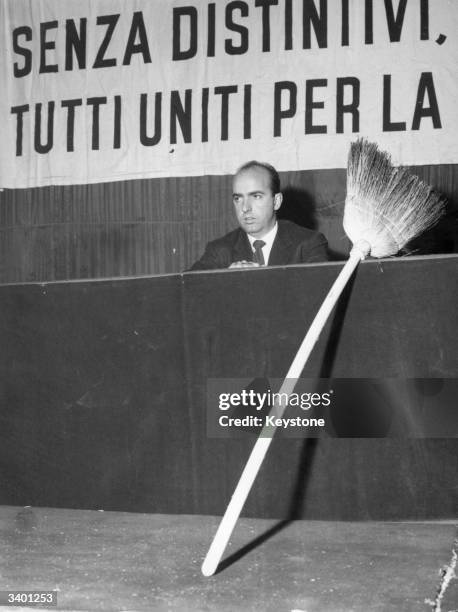 Prince Sforza Ruspoli of Italy, addresses disgruntled Italian farmers at a meeting in Milan. To his left sits a broom, representing the 'broom...