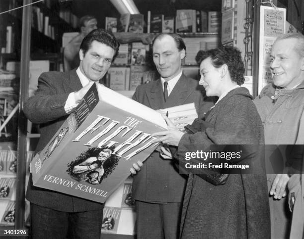 British boxer Freddie Mills signing an oversized copy of writer Vernon Scannell's first novel 'The Fight' outside Panzetta's bookshop in London's...