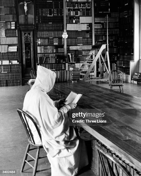 Hooded Trappist monk reads a book in the library of the Abbey of Our Lady of Gethsemane a Trappist monastery in Louisville, Kentucky.