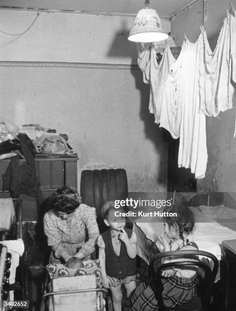 Mother with her three children, living in squalid conditions, washing drying on the line, at Jubilee Buildings in Wapping, a slum building in East...
