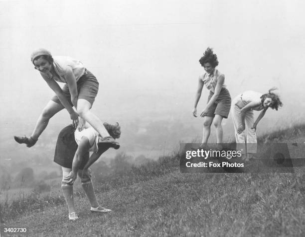 Girls playing a game of leap-frog.