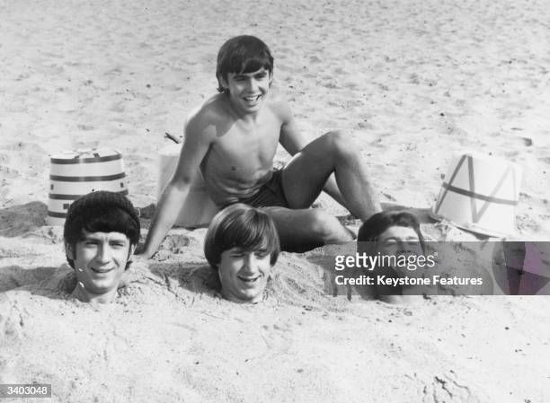 Three members of American pop group The Monkees have been buried up to their necks in sand by fellow group member Davy Jones. Buried members are,...
