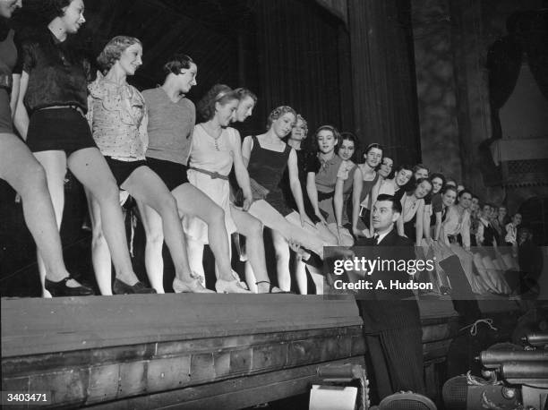 Ralph Reader, the dancing producer, giving instructions to chorus girls during a rehearsal for 'Cinderella' at the Coliseum, London.