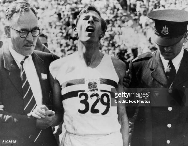 English athletics team manager George Truelove and a police officer help record holder Roger Bannister after what was dubbed 'The Mile Of The...