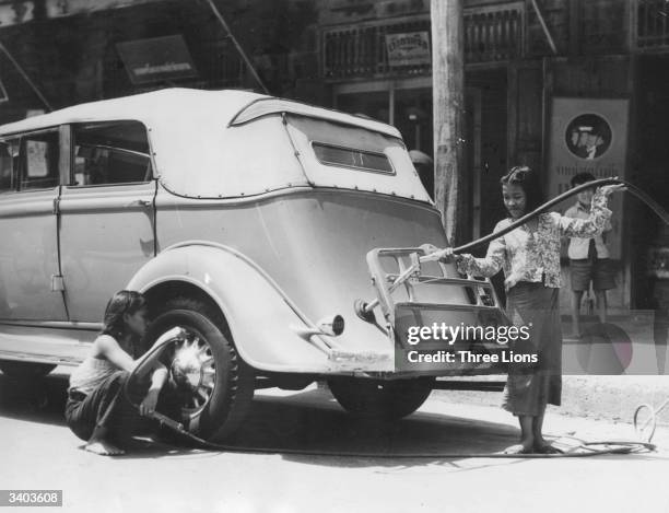 Garage owner's daughter fills a tank and checks the tyres of a car at her father's filling station in Bangkok, Thailand.