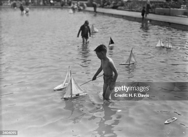 Young boy playing with his toy boat in a children's swimming pool at Rhyl in Wales.