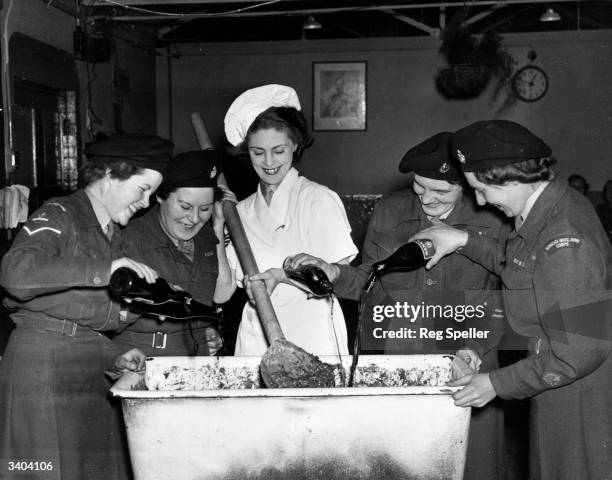 Women of the Women's Royal Army Corp add the requisite amount of alcohol to the mixture, as the Christmas pudding is prepared at the Women's Royal...