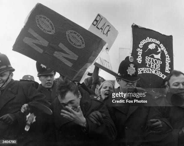 Policeman loses his hat as anti-apartheid demonstrators riot at the St Helen's Rugby Ground, Swansea, Australia, during a match between the South...