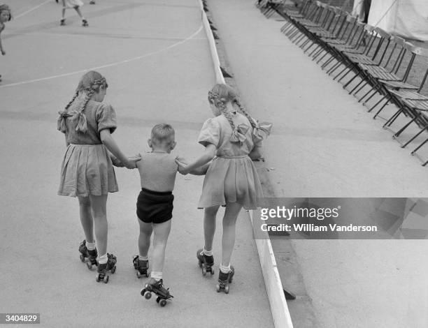 Identical twins Shirley and June Sully give Peter Fry his first skating lesson, at Victoria Park in East London.