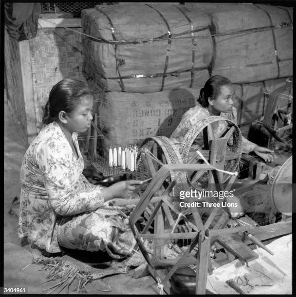 Indonesian textile workers winding bobbins in Java.