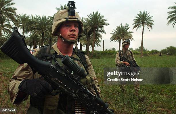 Army soldiers from the 1st Battalion 14th regiment of the 25th Infantry Division advance across an Iraqi palm grove during an operation against...