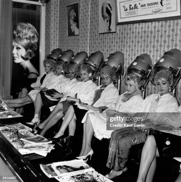 Group of Miss World contestants line up under the hairdryers at La Belle hairdressing salon in Aldwych, London. They include Miss Finland, Miss...