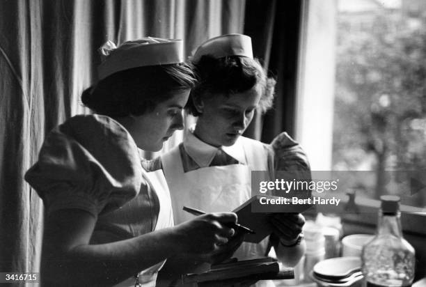 Student nurse, Sylvia Maddele, , checking a patient's chart at the London Hospital. Original Publication: Picture Post - 6780 - I Want To Be A Nurse...