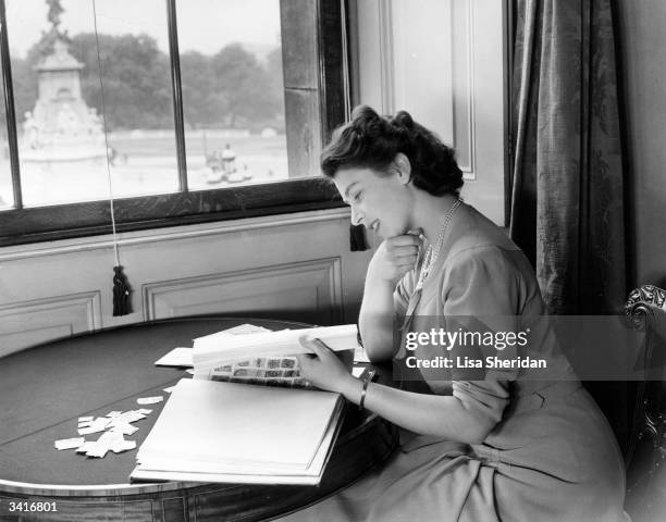 Princess Elizabeth looking through her stamp collection in the State Apartments at Buckingham Palace.