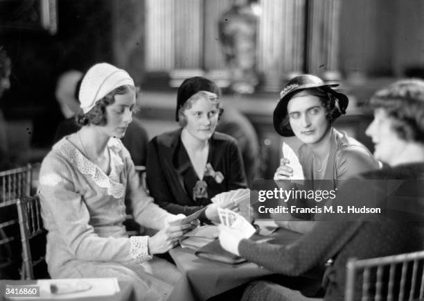 Miss Peggy Lubbock, Miss Lois Hammond and Miss Barbara Cunard engrossed in a bridge tournament at Londonderry House in London.