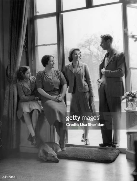 King George VI relaxes with his wife, the Queen Consort Elizabeth, and his children, Princesses Elizabeth and Margaret at the Royal Lodge, Windsor.