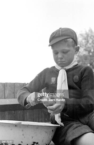 Boy scout of the 7th Royal Eltham Troop earning money for the Boy Scout Association by peeling potatoes. Original Publication: Picture Post - 4779 -...