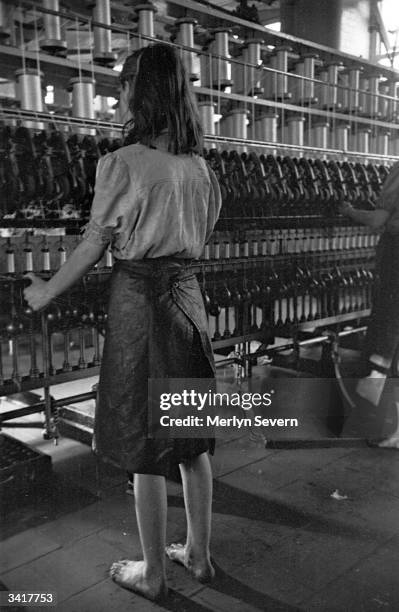 Barefoot girl 'doffer' in a steamy wet spinning mill where Irish linen is produced. Her work is to change the bobbins in the spinning frames....